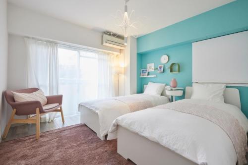 twee bedden in een kamer met een stoel en een raam bij Designer's Apartment 2 bedrooms Shin-OKubo 5minutes walk 蓝 in Tokyo