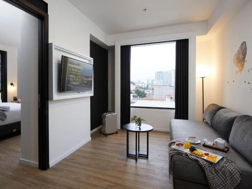 a living room with a couch and a large window at de Braga, ARTOTEL Curated in Bandung