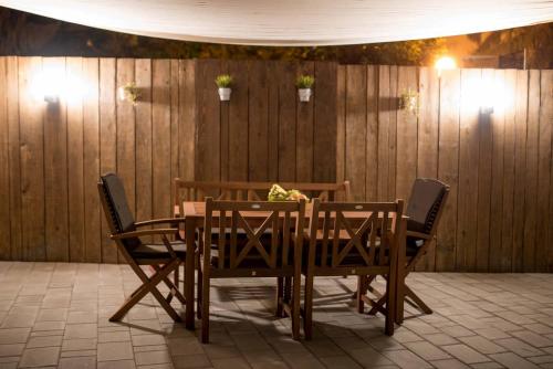 a dining room table with four chairs in front of a wooden wall at Apartman Park in Daruvar