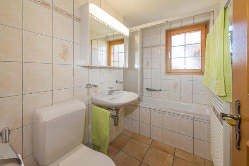 een badkamer met een toilet, een wastafel en een bad bij Paradiso 2 in Grächen