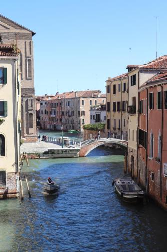 a boat in a river with buildings and a bridge at Palazzo Vendramin Costa in Venice