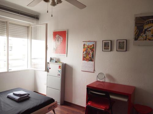 a bedroom with a bed and a table and a refrigerator at Habitaciones frente a la playa in Málaga