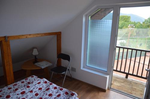 a bedroom with a bed and a desk and a window at Baza Sportiva Adelina in Cîmpulung