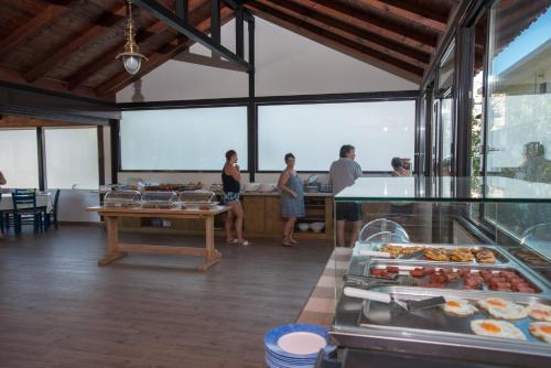 a group of people standing in a kitchen with food at Paradise Matala Hotel in Matala