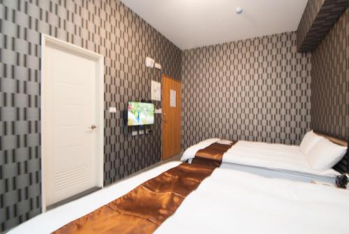 a bedroom with a bed and a tv and a door at Yixiang Spring Travel in Jiaoxi