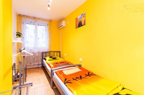 two beds in a room with yellow walls at CentralComfortBDPST in Budapest