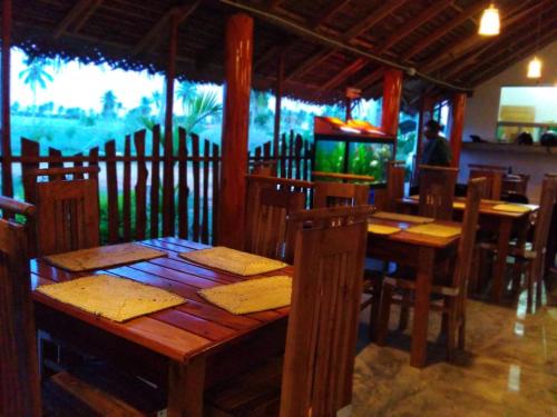 a wooden table and chairs in a restaurant at Shan Guest and Restaurant Nilaveli in Trincomalee