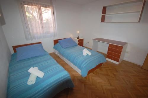 a bedroom with two twin beds and a desk at Apartments Daidzic in Njivice