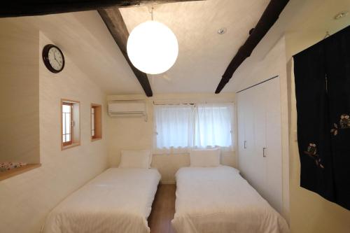 2 camas en una habitación con un reloj en la pared en Kokon Higashiyama, en Kioto