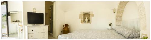 a bedroom with a bed and a flat screen tv at Marinelli Guest House in Cisternino