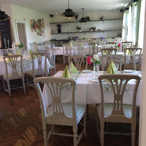 a dining room with white tables and chairs with flowers at Tunneberga Gästgifvaregård in Jonstorp