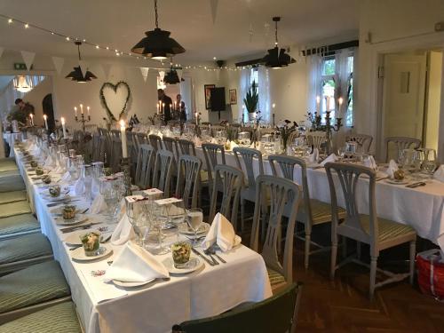 una mesa larga con mesas blancas y sillas en una habitación en Tunneberga Gästgifvaregård, en Jonstorp