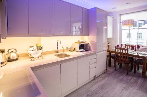 een keuken met paarse kasten en een eetkamer bij Victoria Violet in Londen
