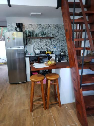 a kitchen with a counter with two stools and a refrigerator at Casinhas da Julieta in Morro de São Paulo