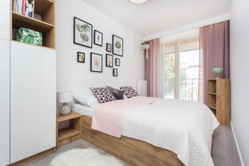 a white bedroom with a bed and a window at City of the Kings - Pastel Apartment Lubelska 10 in Krakow