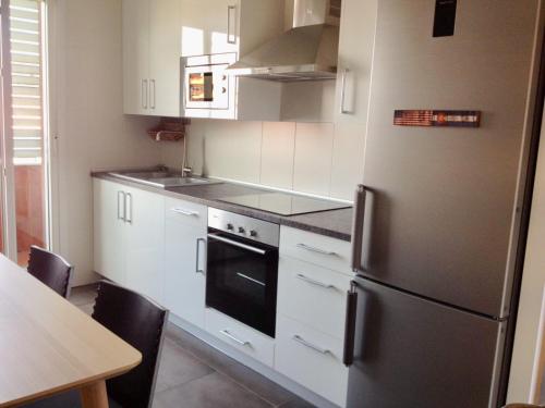 une cuisine avec des armoires blanches et un réfrigérateur en acier inoxydable dans l'établissement Bermeo y Urdaibai - PARKING-Ascensor - WIFi - tranquilo, à Bermeo