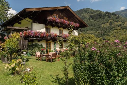 a house with a table and chairs and flowers at Haus Knapp FeWo Gastein in Dorfgastein
