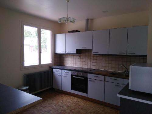 a kitchen with white cabinets and a window at La maison de Jacques in Villiers-en-Morvan