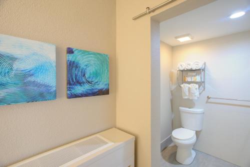 a bathroom with a toilet and two paintings on the wall at Beachview Club Hotel in Jekyll Island