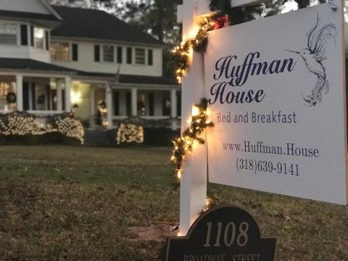 una señal frente a una casa con luces de Navidad en Huffman House Bed & Breakfast, en Minden