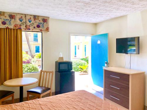 een slaapkamer met een bed en een televisie en een tafel bij Dunes Inn & Suites - Tybee Island in Tybee Island