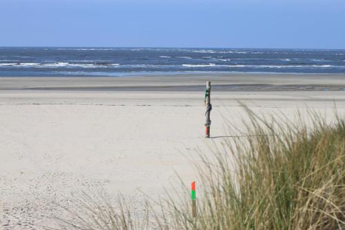 a person standing on a beach near the ocean at Hotel Strandhof in Baltrum