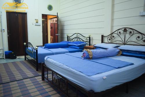 three beds in a room with blue pillows on them at Teratak Ibunda Guest house in Kota Bharu