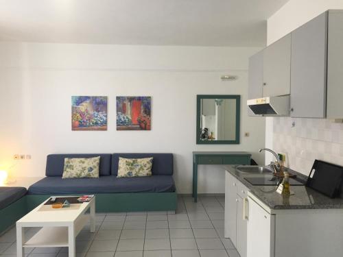 a living room with a blue couch and a kitchen at Evdokia Suites in Gouves
