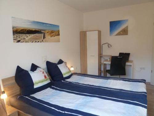 1 dormitorio con cama con sábanas azules y escritorio en Memmert en Horumersiel