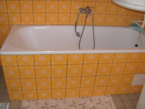 a bath tub in a bathroom with an orange tiled wall at Krkonosska Chalupa in Semily