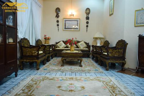 - un salon avec des canapés, une table et des chaises dans l'établissement Teratak Ibunda Guest house, à Kota Bharu