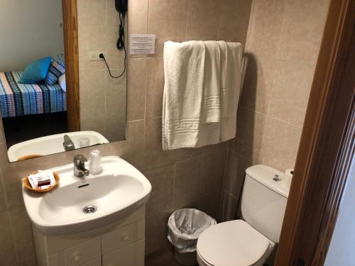 Un baño con lavabo, inodoro y espejo. en Posada Tintes, en Cuenca