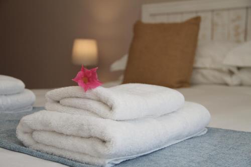a stack of towels with a flower on a bed at The Vine in Klawer