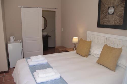 a bedroom with a white bed with towels on it at The Vine in Klawer