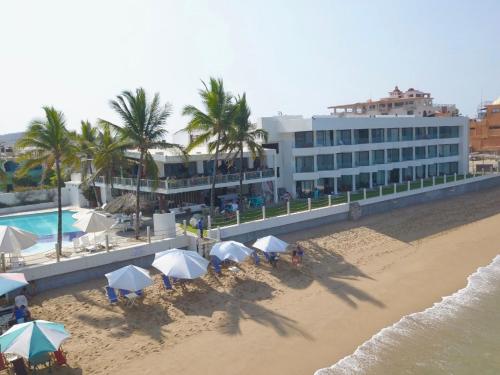 Hotel Barra de Navidad في بارا دي نافيداد: فندق فيه شاطئ فيه مظلات ومبنى
