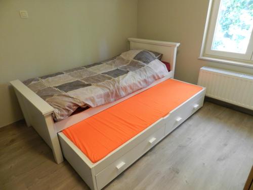 a small bedroom with a bed with an orange mattress at Fleur d’ Amour in Heuvelland
