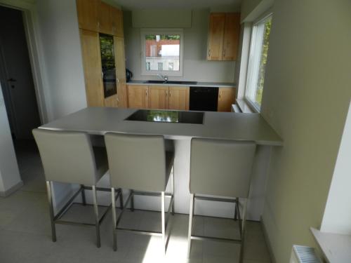 a kitchen with a counter with chairs around it at Fleur d’ Amour in Heuvelland
