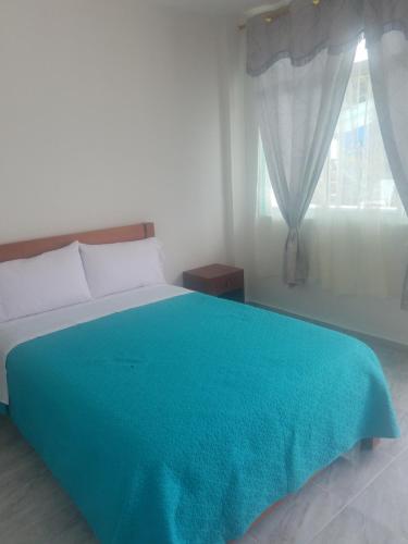 a bedroom with a bed with a blue blanket on it at Hotel Villa Turquesa in Tonsupa