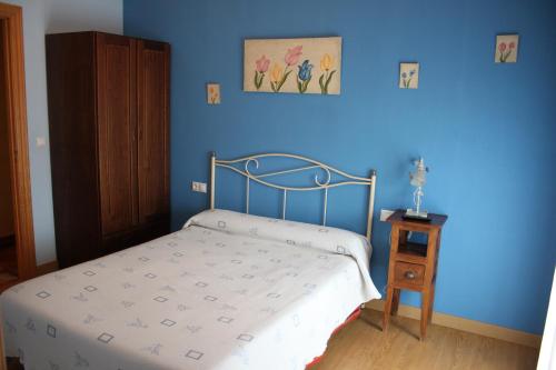 1 dormitorio con cama y pared azul en El Rincon del Labrador, en La Santa Espina