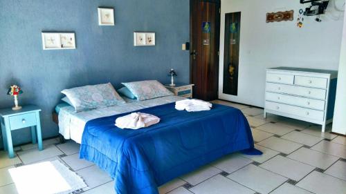 a bedroom with a blue bed with two towels on it at Chalés Bocaina in Ilhabela