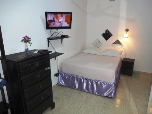 a bedroom with a bed and a dresser and a tv at Aparta hotel El Sol, Home near AirPort SDQ in Boca Chica