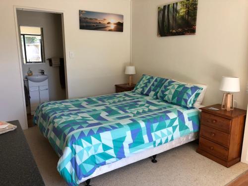 a bedroom with a bed with a blue and white comforter at Hahei Retreat in Hahei