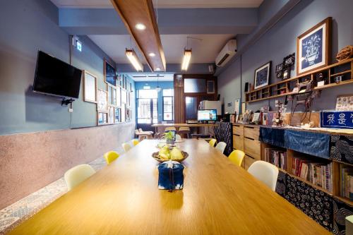 a long wooden table in a room with chairs at Local Backpacker Hostel in Tainan