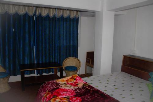 a bedroom with a bed and a window with blue curtains at Riva homestay family room in Darjeeling