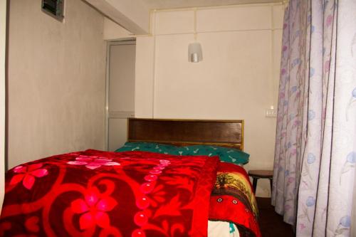 a bedroom with a bed with a red blanket at Riva homestay family room in Darjeeling