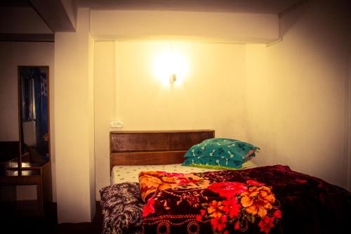 a bed in a room with a light on the wall at Riva homestay family room in Darjeeling