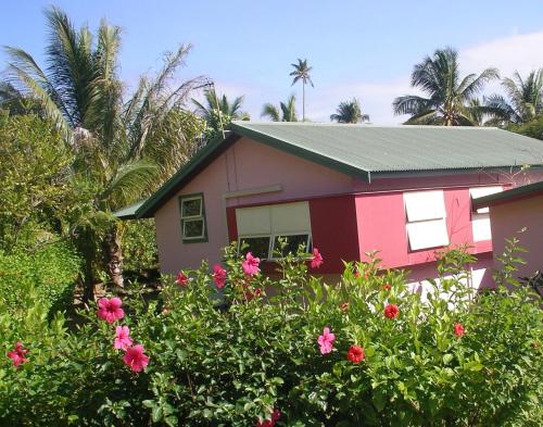 ein rosa Haus mit Blumen davor in der Unterkunft Hibiscus House in Flying Fish Cove