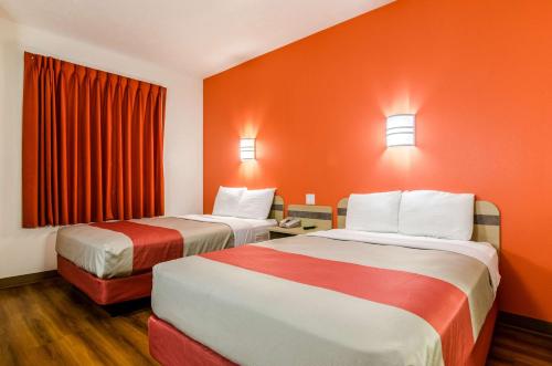 two beds in a hotel room with orange walls at Motel 6-Kearney, NE in Kearney