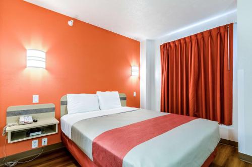 a bedroom with a large bed with orange walls at Motel 6-Kearney, NE in Kearney