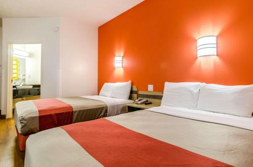a hotel room with two beds with orange walls at Motel 6-Kearney, NE in Kearney